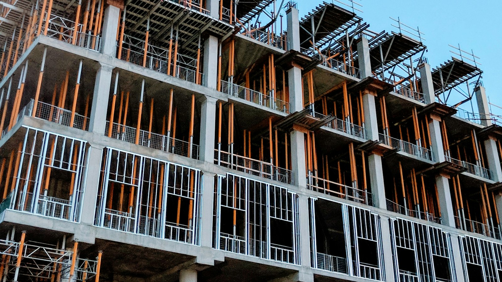A grey concrete building under construction against a pale sky, its frame exposed mid-build.