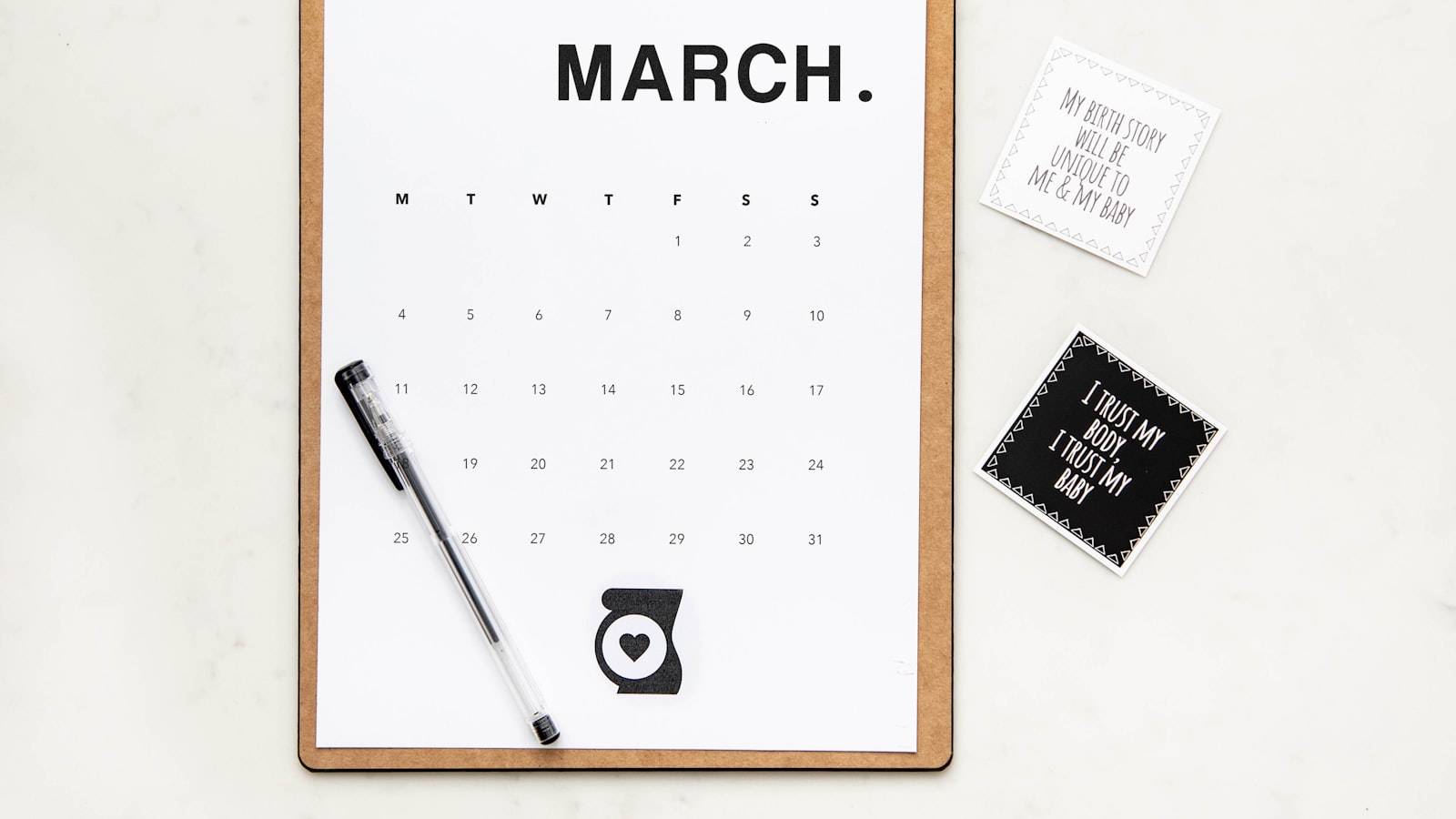 An open desk calendar with a pen laid across it in a minimalist, top-down composition.