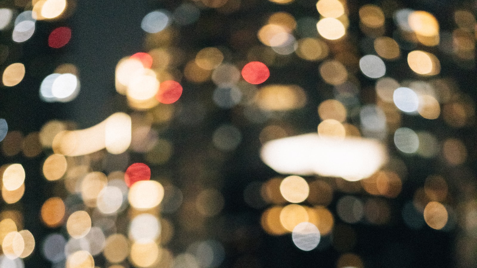 Blurred, dreamlike bokeh of city lights at night, out of focus and glowing.
