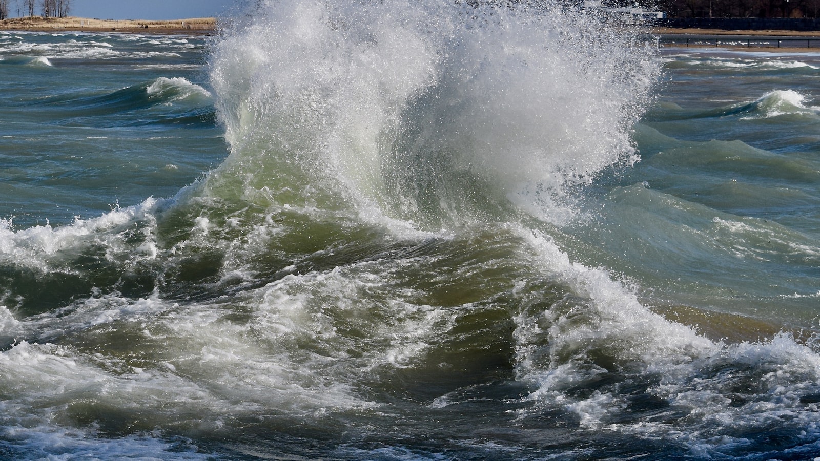 Two ocean waves crashing into each other and colliding in a burst of white spray.