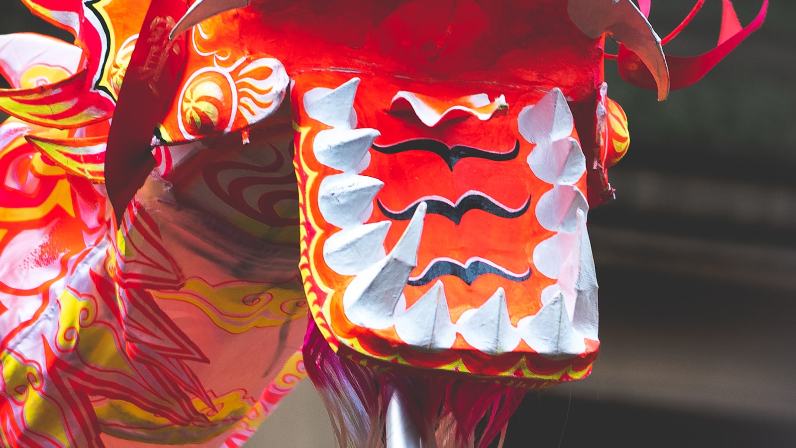 A red and gold Chinese dragon costume performing a dragon dance in the street during a Lunar New Year parade.