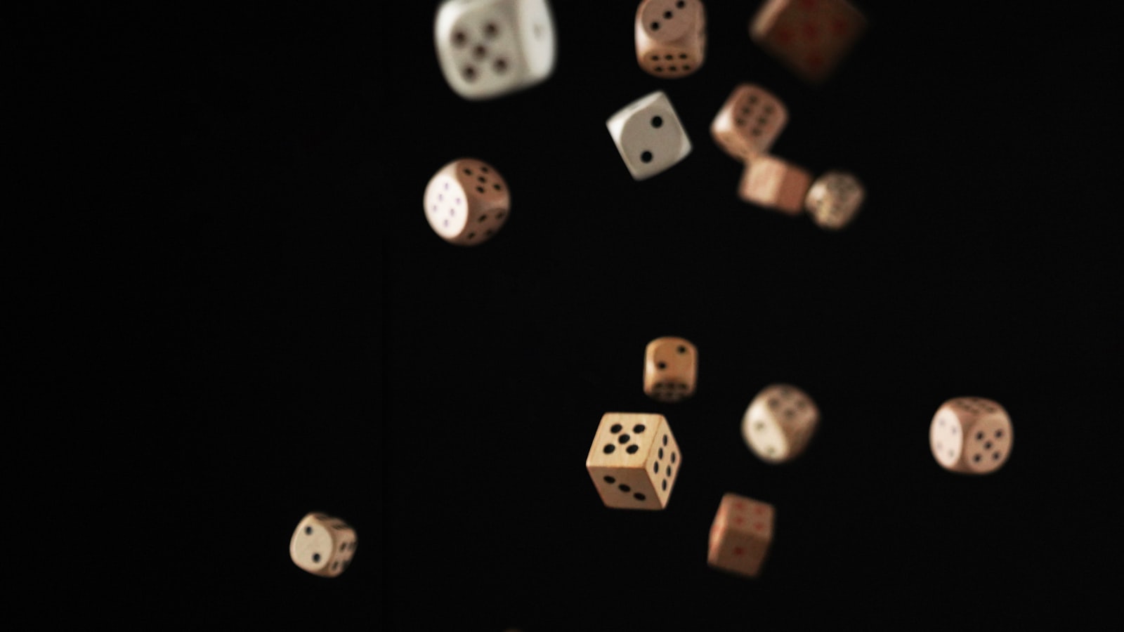 Multiple dice tumbling and suspended mid-air against a black background, as if just thrown
