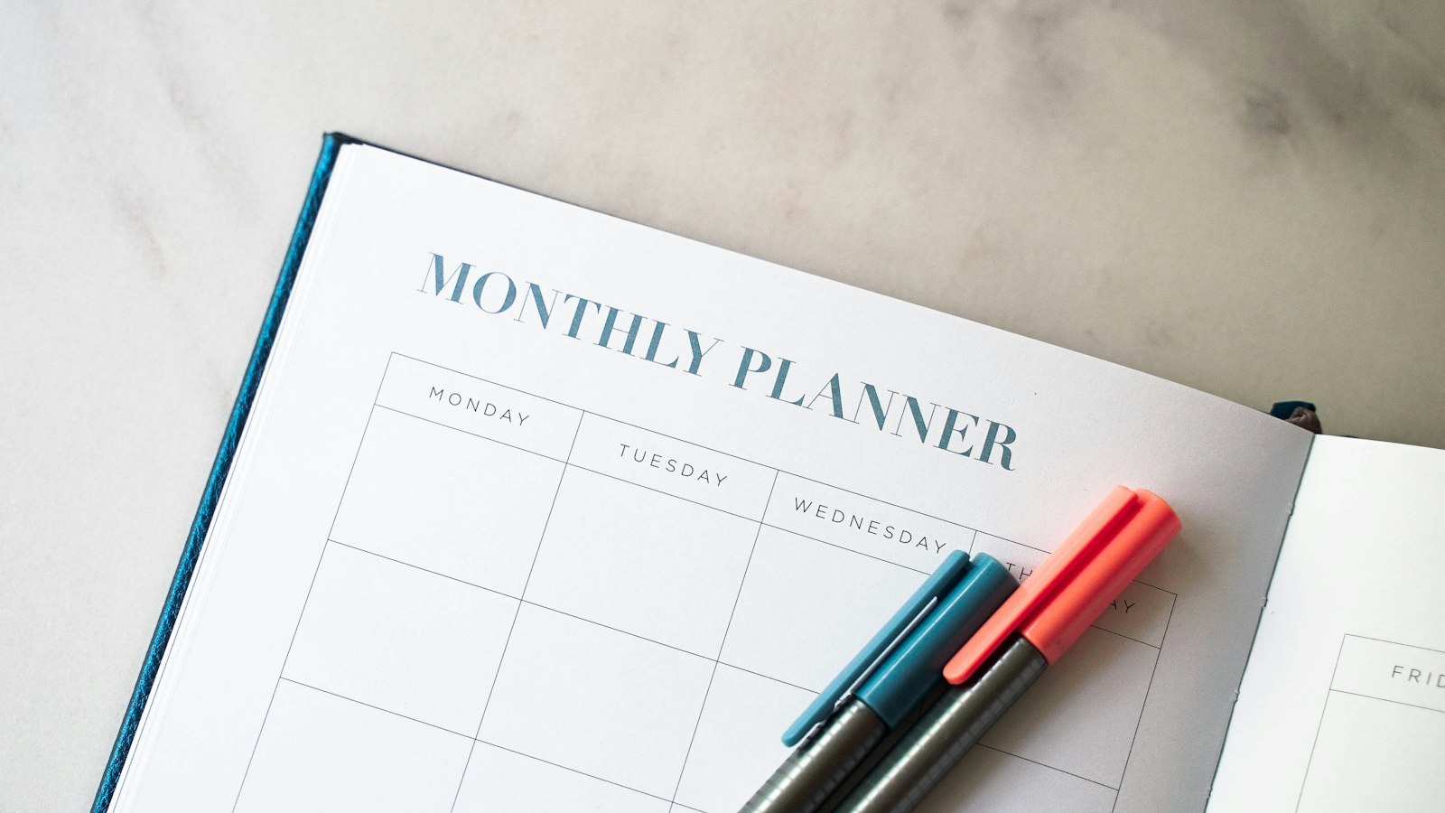A planner with two pens resting on top of it