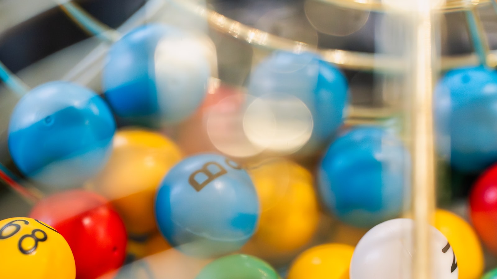 Colorful numbered lottery balls tumbling inside a spinning draw cage