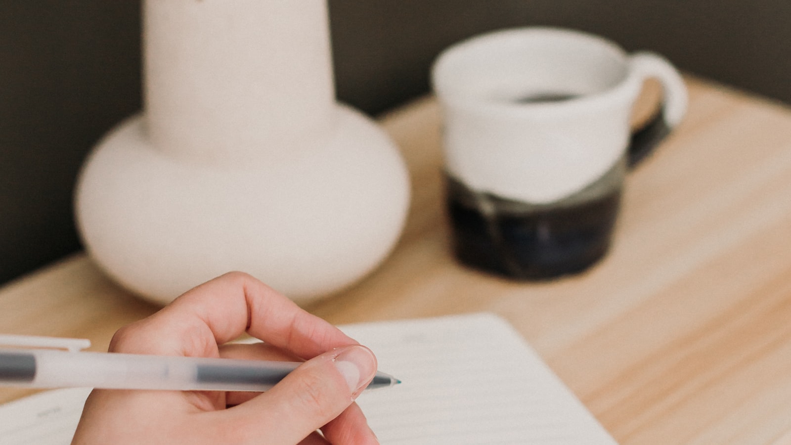 A close-up of a hand writing with a pen in an open notebook, weighing a decision on paper.